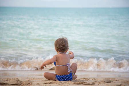 adorable toddler girl playing on sandy beach of tropical island. summer holidayの写真素材