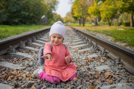 portrait of little girl sitting on the train tracks in the forest