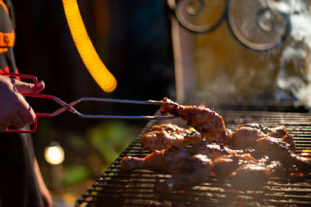 chicken drumsticks are grilled on a barbecue grill in the evening