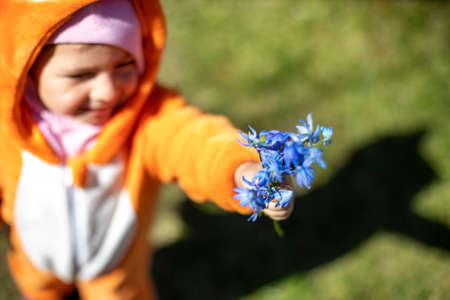 adorable toddler with spring flowers outdoors in sunlight