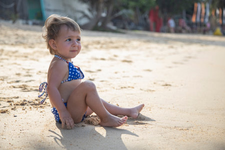 adorable toddler girl playing on sandy beach of tropical island. summer holidayの写真素材