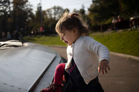 adorable toddler climbs the fountain in the park. weekend walk with children in park in good weatherの写真素材