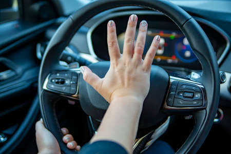 female hand presses the horn on the steering wheel of a modern car. no faceの写真素材