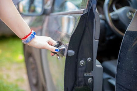 a woman's hand opens drivers door of a black car