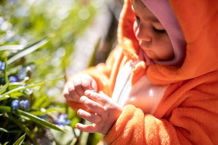 adorable toddler with spring flowers outdoors in sunlightの写真素材
