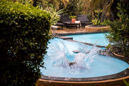 splash of water after jumping into a tropical outdoor pool in the pouring rain.