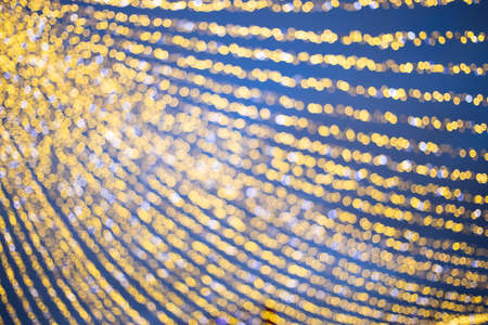 Christmas holiday background, shining garland in the blue evening frozen sky at New Year's street...