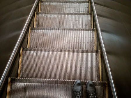 feet on the escalator top view. a human rides an escalator down the subwayの写真素材