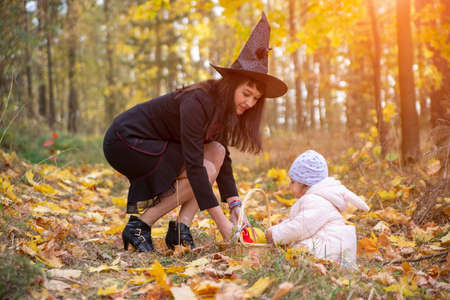 black witch woman with little toddler bunny in the autumn forest. halloween celebration, costume...