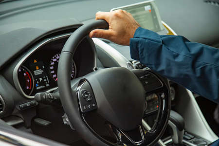 male hand on the steering wheel of a modern car. multifunction steering wheel and driver's panel. no...
