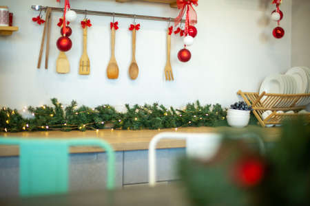 Kitchen wooden countertop with hob and kitchenware decorated for winter holidays new year christmas