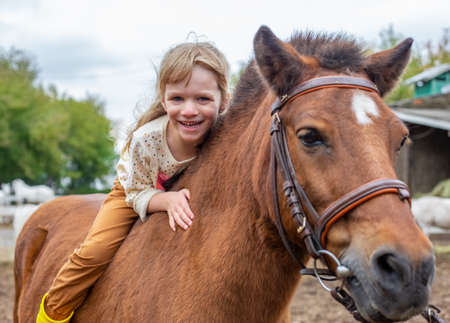 happy little girl riding pony horse bareback and laughの写真素材