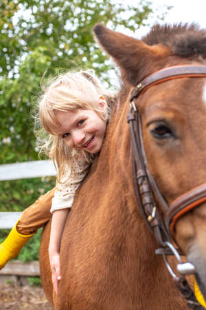 little girl hugs pony horse and laugh happilyの写真素材