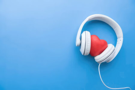 Headphones with a red heart inside, symbolizing love and music on a blue surface
