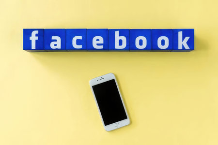 Simple image of Facebook logo with blocks and smartphone on bright yellow background