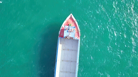 A boat floating on calm, clear blue water, viewed from above.