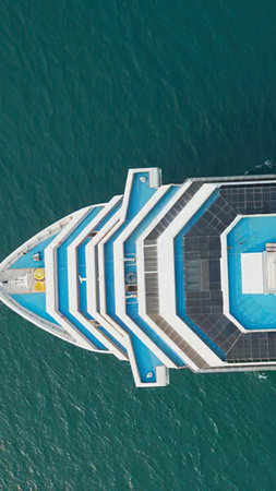 An aerial view of a big cruise ship floating in calm blue ocean water.