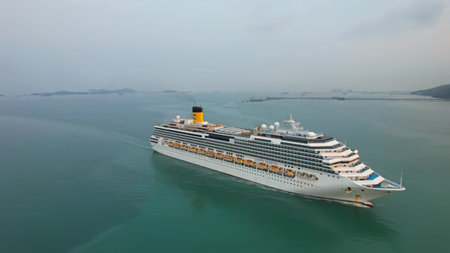 A big cruise ship moving through peaceful ocean water under cloudy sky.