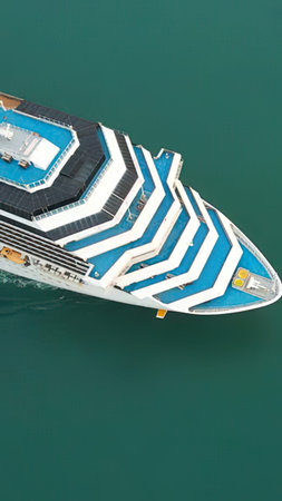 Aerial view of a large cruise ship with blue and white colors floating on calm water