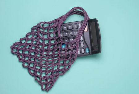 A calculator partially covered with a purple mesh net bag on a blue background.