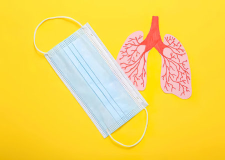 Face mask and lungs drawing on bright yellow background for health topic