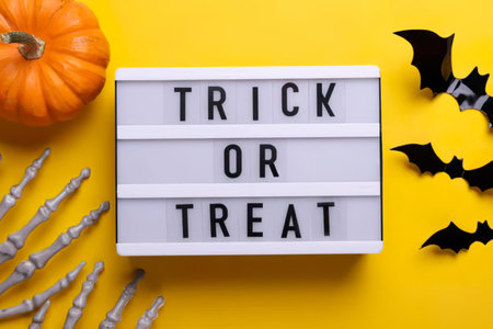 Festive Halloween scene with lightbox, pumpkin, and bats on yellow background