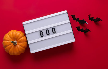 A festive Halloween scene with a pumpkin, bats, and a message board