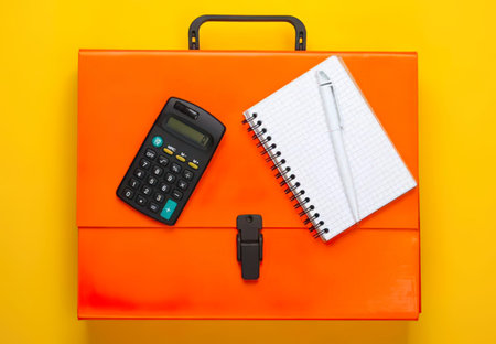 A bright office desk scene with calculator, notebook, and orange briefcase on yellow background