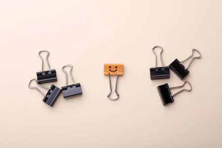 Simple image showing a smiley face clip surrounded by black clips on a light background