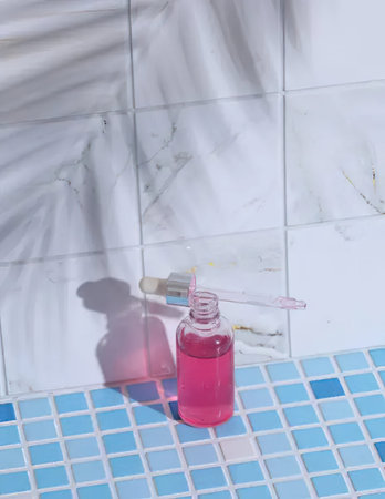 A pink soap dispenser with a pump sits on blue tiles in a bathroom setting.