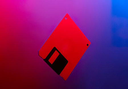 A vintage red floppy disk icon floating on a vibrant purple and blue gradient background.