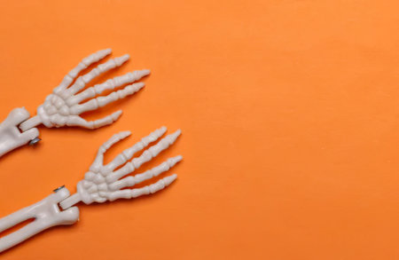 Plastic skeleton hands placed on an orange surface, creating a spooky effect