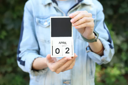 Woman holding calendar with date of April 2, closeup of photo