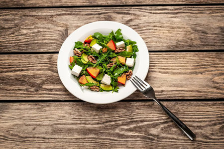 Salad with arugula, feta cheese and pumpkin on wooden background