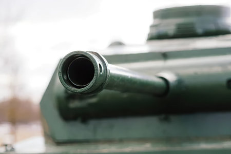 A detailed close-up of a military tank barrel with a blurred outdoor background.
