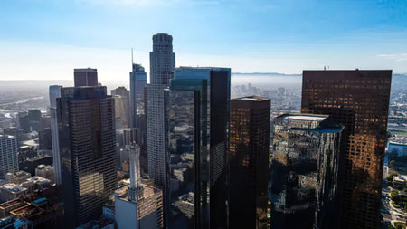 A wide view of a busy city skyline featuring skyscrapers and a clear blue sky.