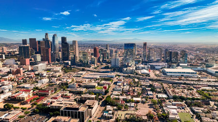 A wide view of a city skyline with skyscrapers, blue sky, and clouds.