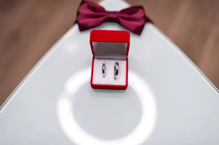 Elegant wedding rings in a red box with a bow on a white table