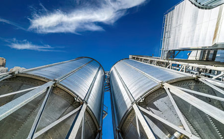 Big metal tanks in an industrial setting, with a clear blue sky above.