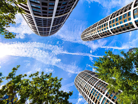 View from ground of tall glass skyscrapers with blue sky and clouds