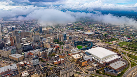 An aerial shot showing city buildings, roads, and green parks from above.