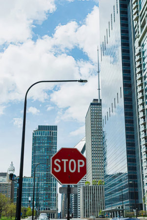 A vibrant city street with tall skyscrapers, street signs, and a stop sign.
