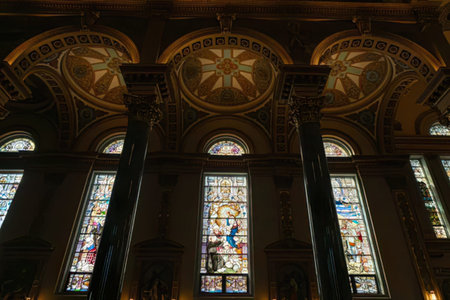 Inside a church showing stained glass windows, tall columns, and decorative ceiling.