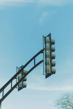 A traffic light mounted on a tall pole against a bright blue sky background.