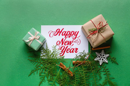 Holiday scene with wrapped presents, greenery, and a New Year card on green background