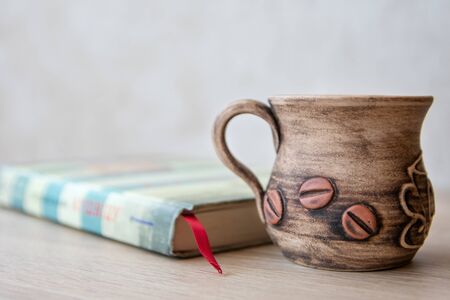 Cup of coffee with books on the table. Books in the house. Books and cup of coffee or tea on a wooden table. Cup of coffee with open book on the tableの写真素材