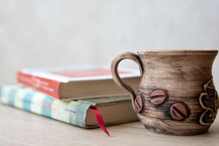 Cup of coffee with books on the table. Books in the house. Books and cup of coffee or tea on a wooden table. Cup of coffee with open book on the tableの写真素材