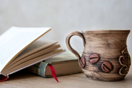 Cup of coffee with books on the table. Books in the house. Books and cup of coffee or tea on a wooden table. Cup of coffee with open book on the tableの写真素材