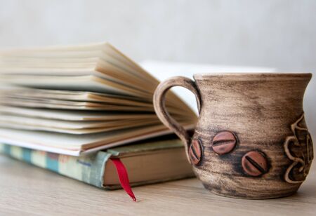 Cup of coffee with books on the table. Books in the house. Books and cup of coffee or tea on a wooden table. Cup of coffee with open book on the tableの写真素材