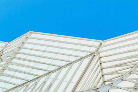 Minimal futuristic architectural composition featuring white geometric steel and glass structures beneath a vibrant blue sky.